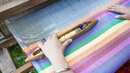 person weaving on a loom